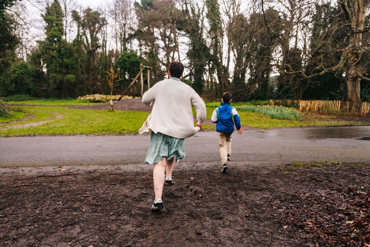Family photographer Dublin Ireland  Two people running together on a muddy park path.