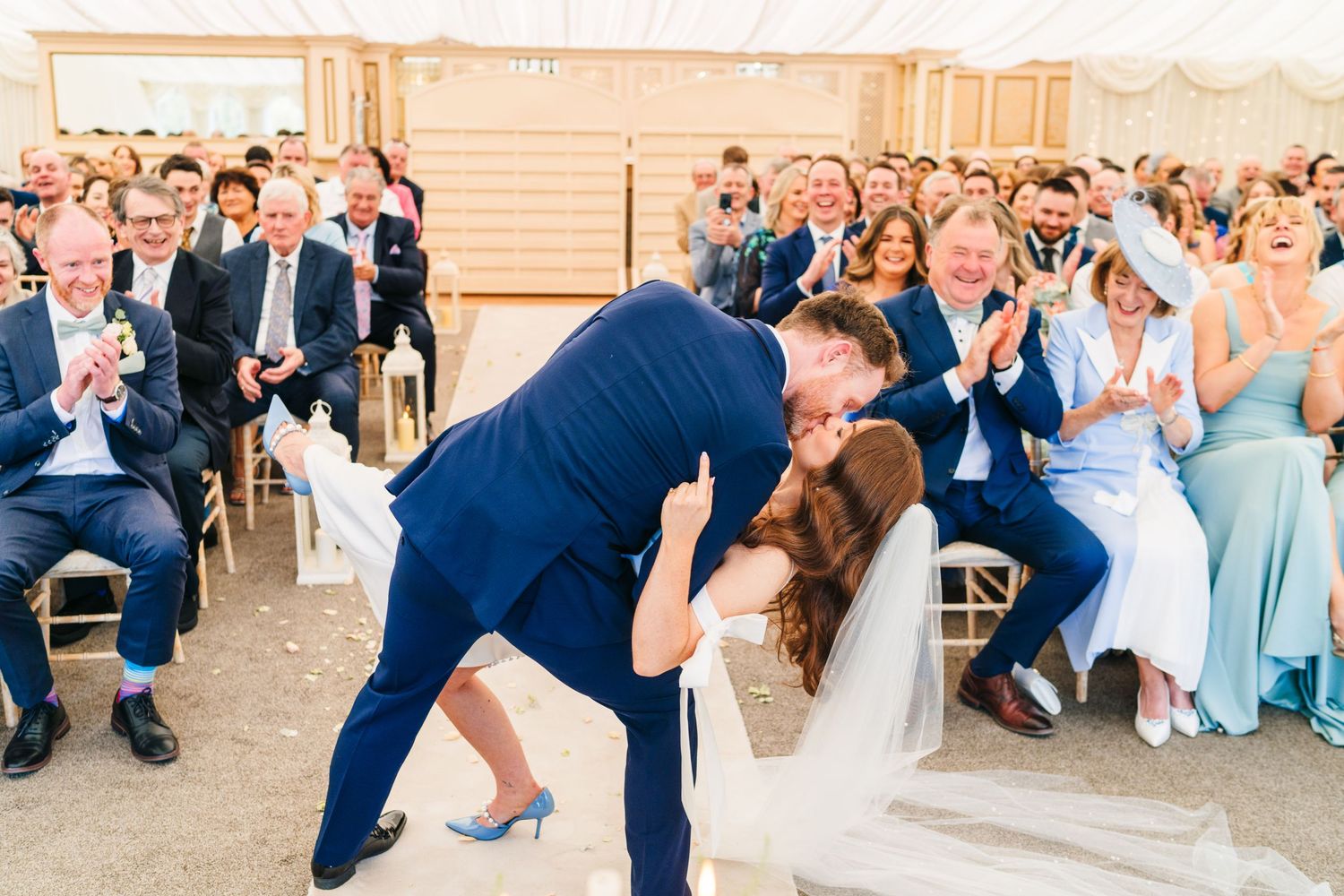 Castle Leslie Wedding Photographer DublinWedding celebration in a bright tent venue with guests in formal attire watching a special moment.