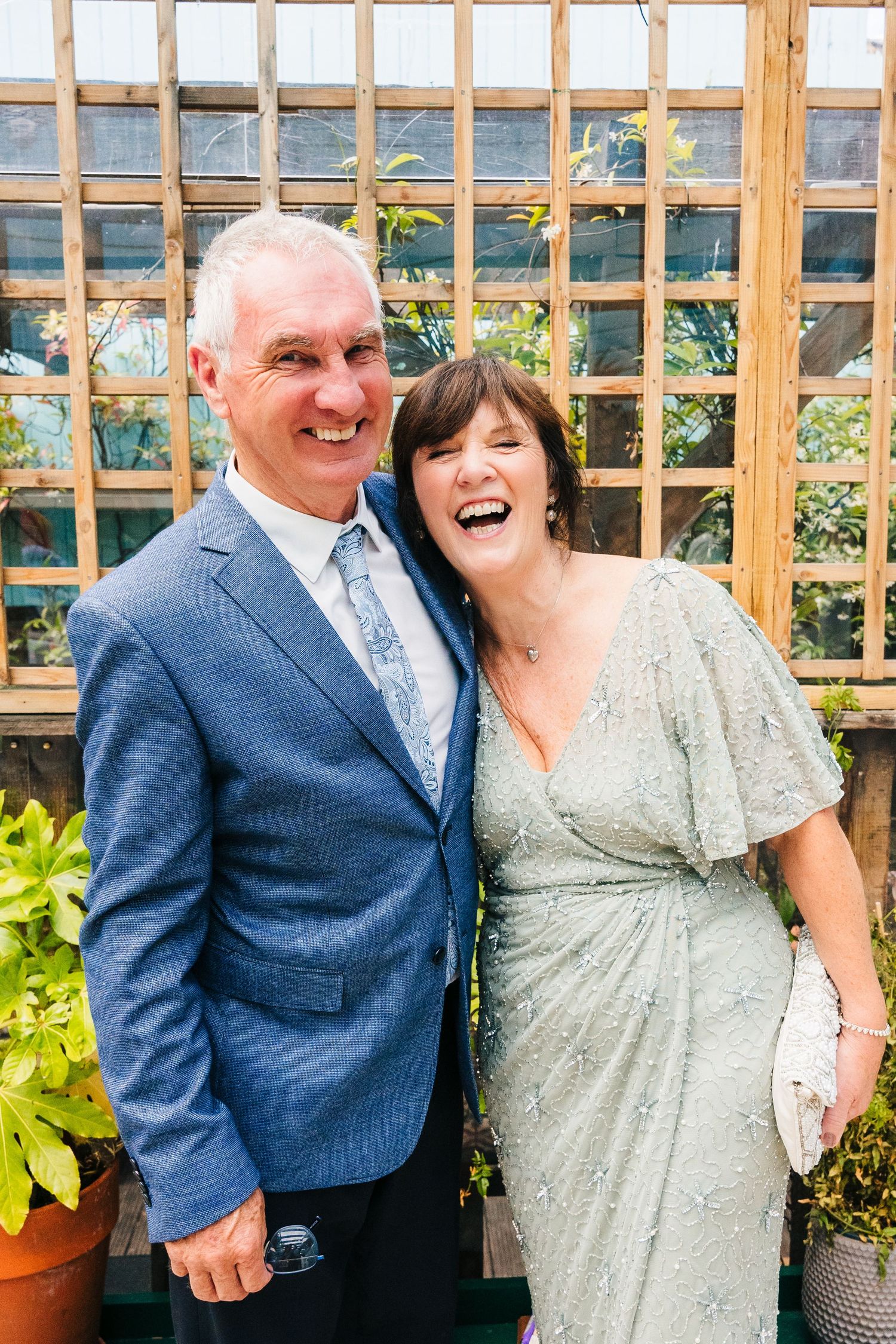 A couple shares a joyful moment together in front of a garden trellis. House Dublin Wedding Photographer