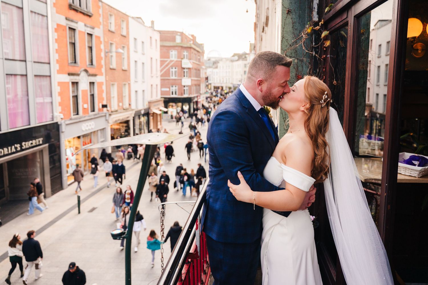 A couple shares an intimate moment on a balcony overlooking a busy Dublin street. Wedding Photographer Dublin