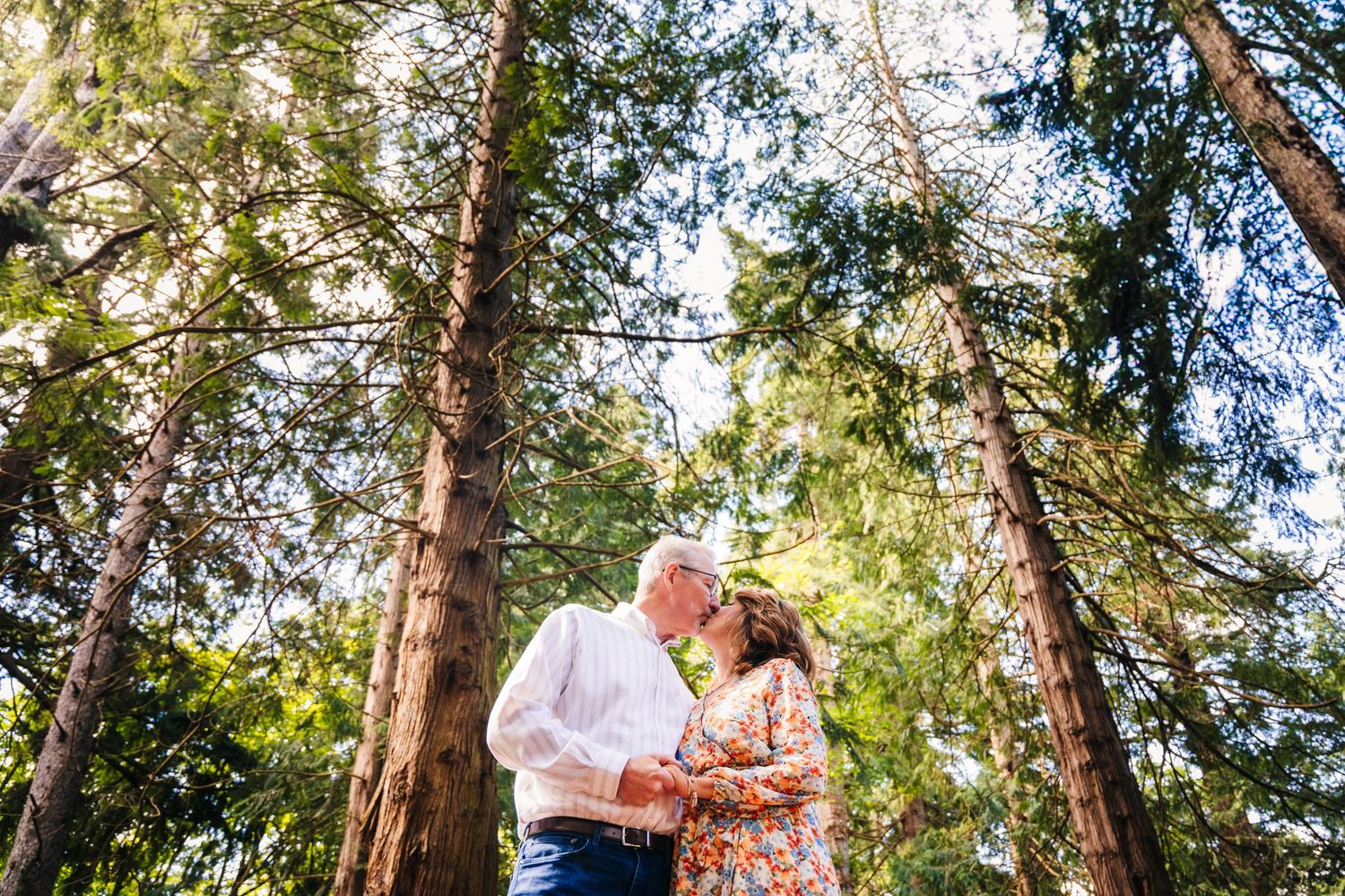 A couple in coordinating pink and blue outfits embrace among tall forest trees during a romantic photoshoot. PHOTOGRAPHER Dublin ireland
