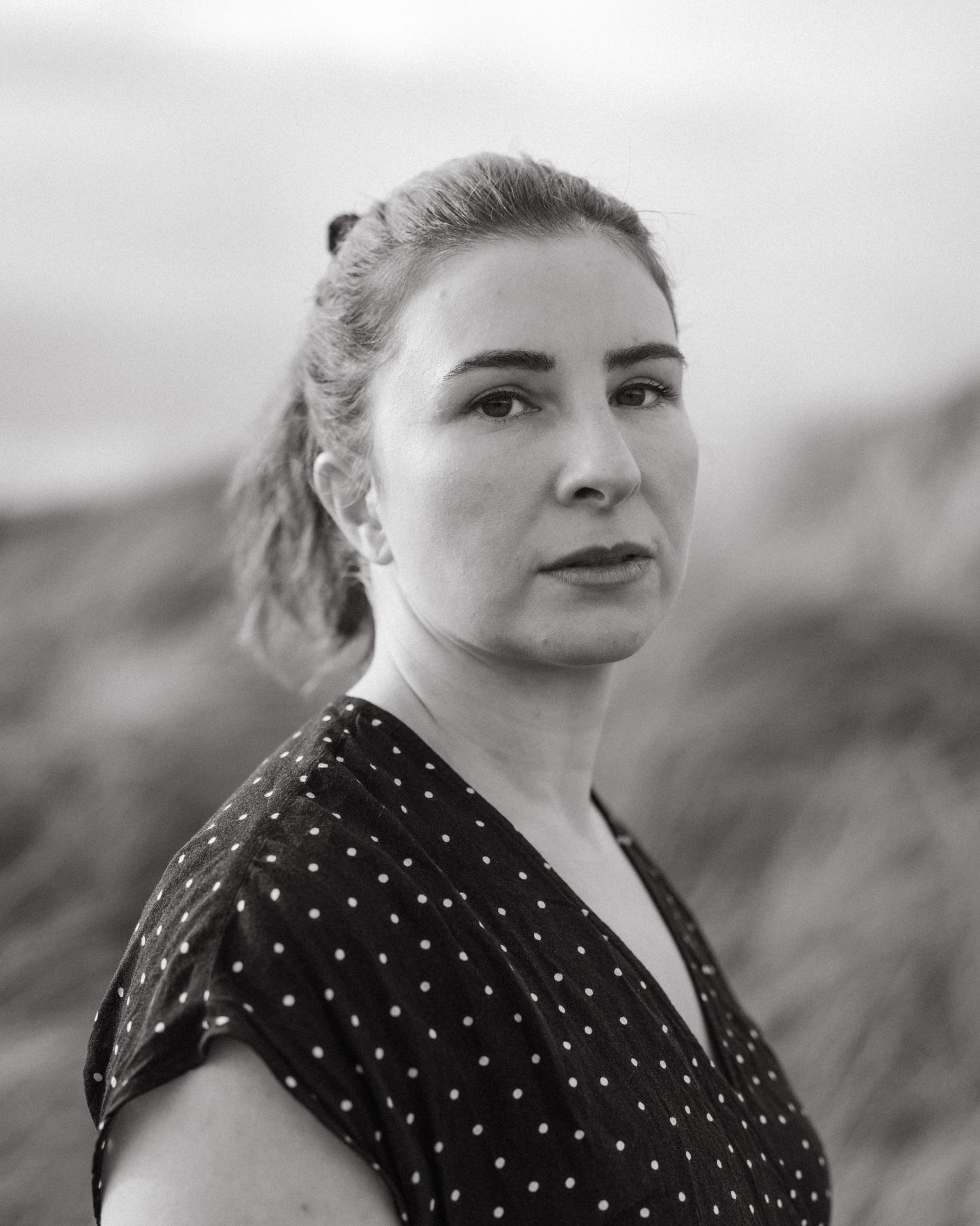 Black and white portrait wearing polka dot dress against blurred natural landscape. PHOTOGRAPHER Dublin ireland