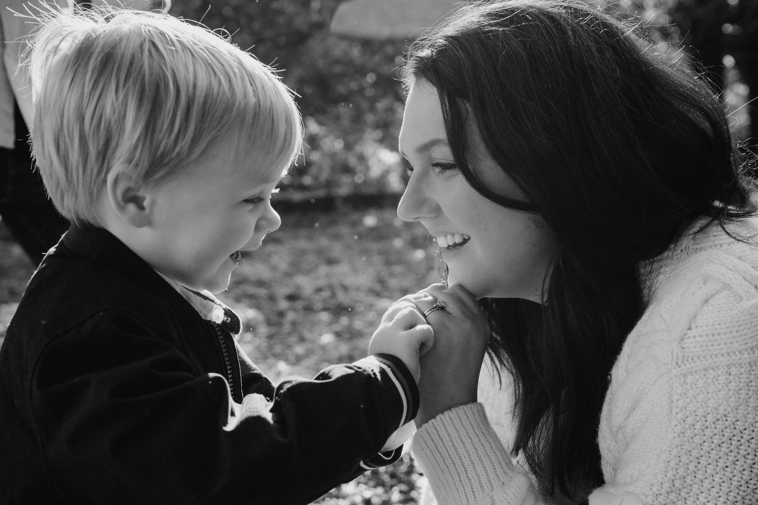 A tender black and white photograph showing a heartwarming interaction between an adult and young child outdoors. family PHOTOGRAPHER Dublin