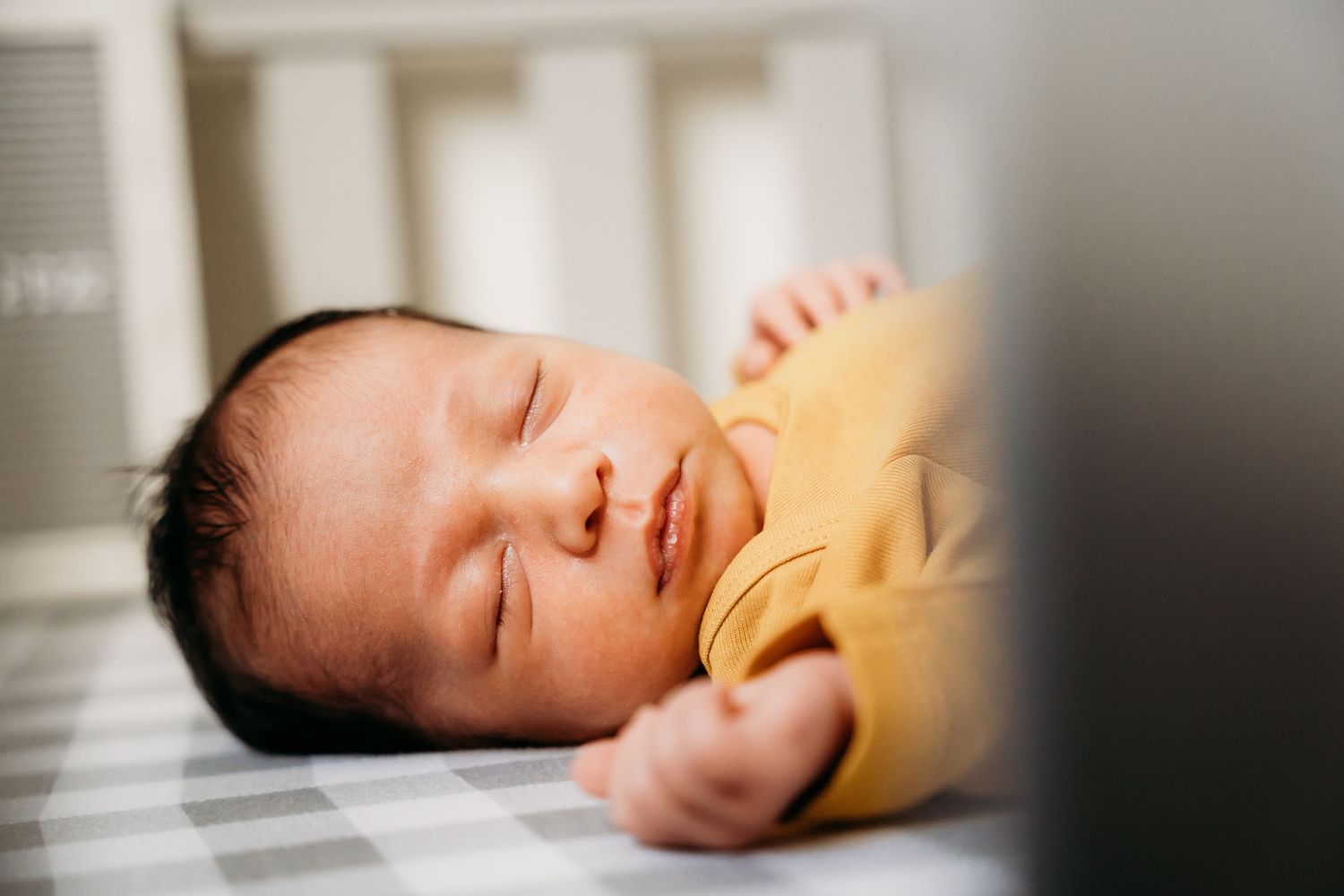 Peaceful sleeping infant lying on white bedding in soft natural light. family PHOTOGRAPHER Dublin