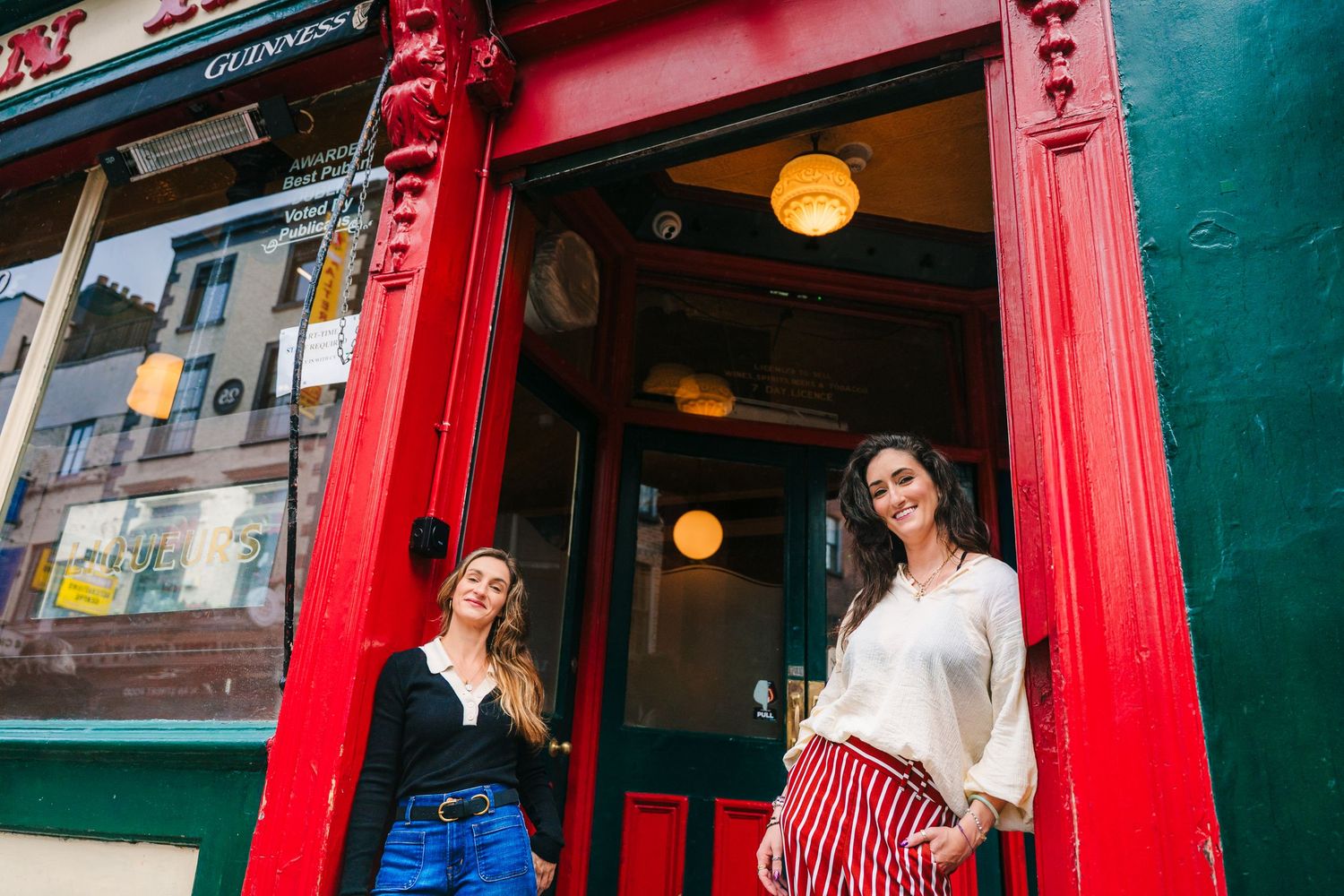 Dancing couple in front of a vibrant red storefront with retro signage and architecture. professional headshots dublin photographer