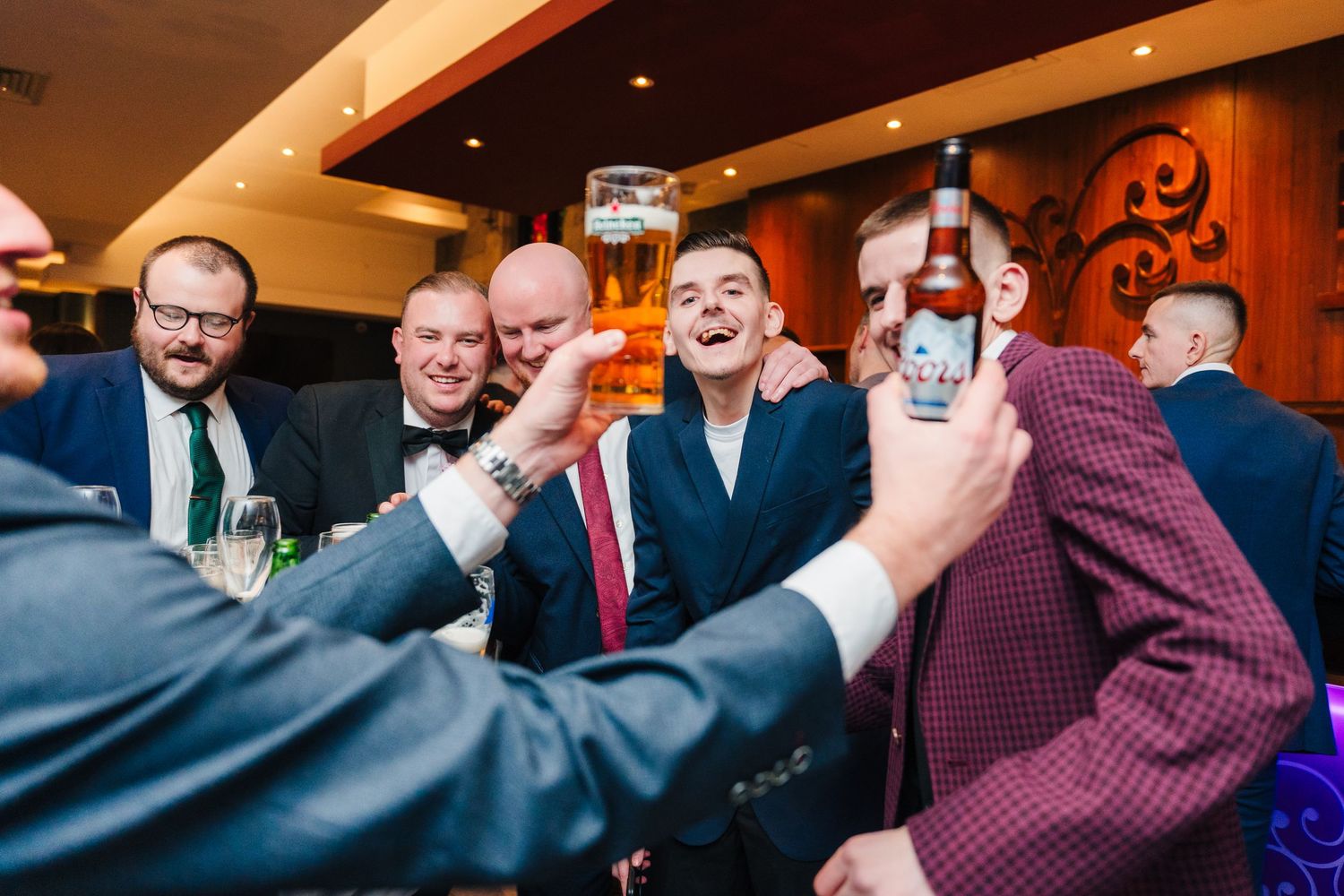 Wedding reception guests enjoying themselves in a warmly lit indoor venue. Wedding photographer dublin