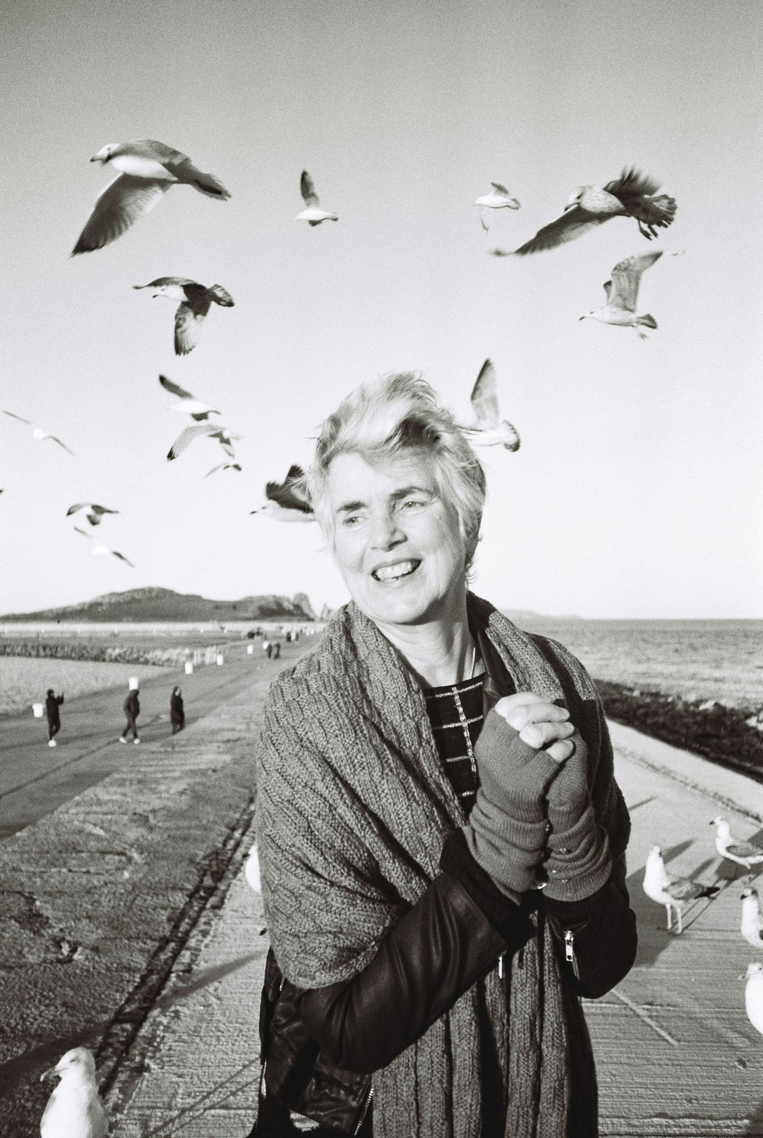 Black and white sequence showing a person joyfully interacting with seagulls at a seaside boardwalk. HEADSHOTS DUBLIN