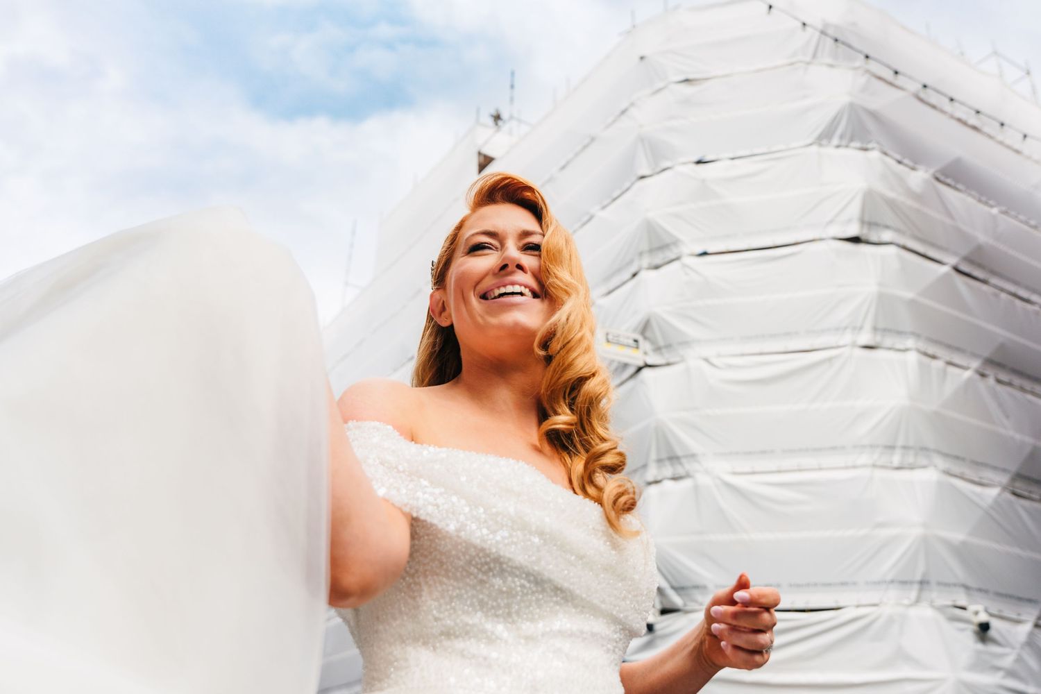 Joyful bridal portraits with flowing white dress against bright sky background.  city hall dublin wedding photos