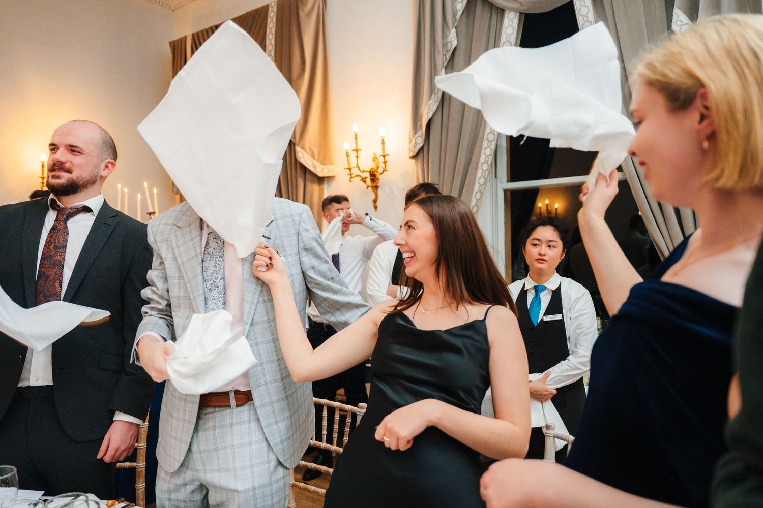 Wedding guests celebrate by waving white napkins during a joyous reception moment. Wedding Photographer Dublin