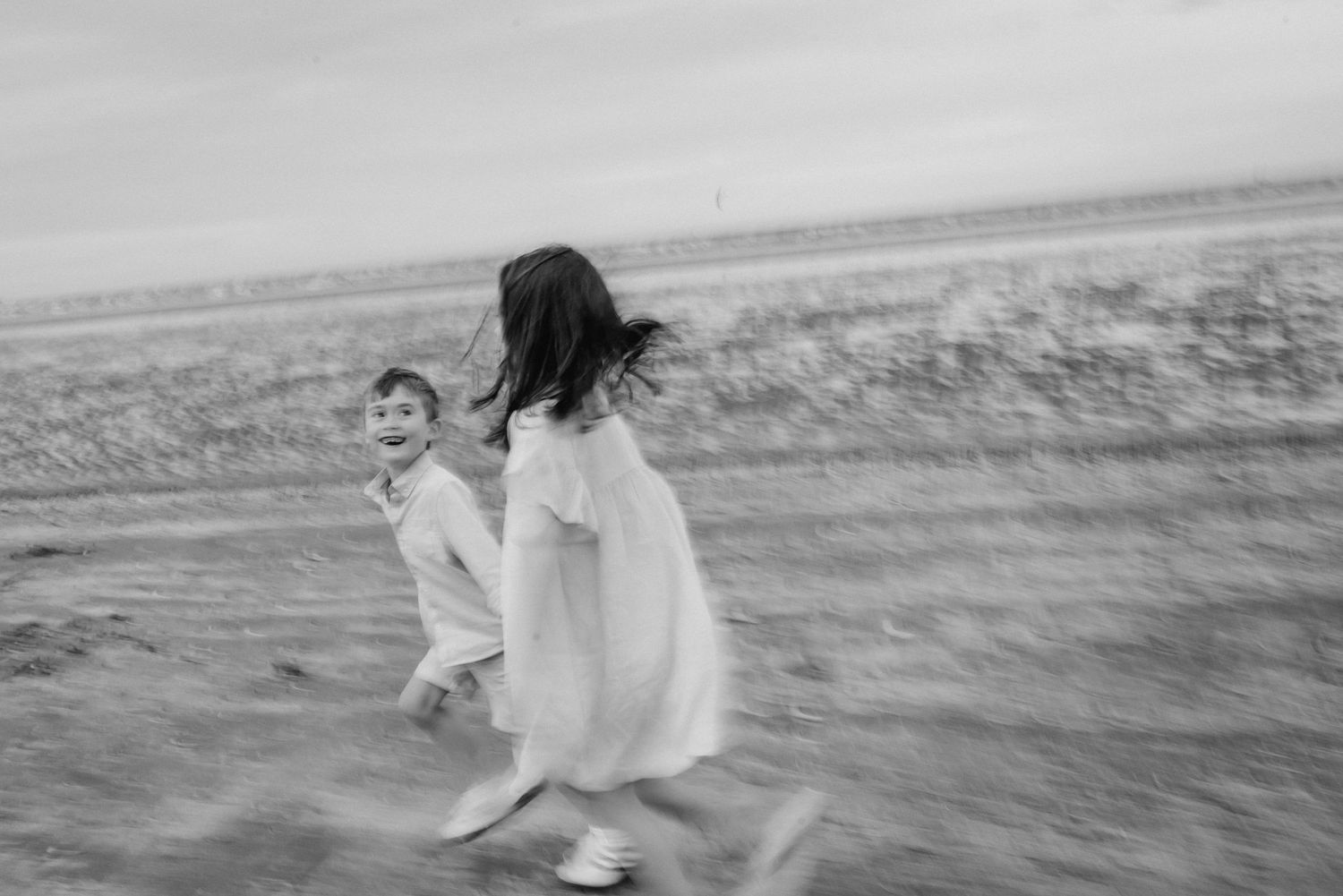 Black and white beach photos showing dynamic movement and joy in natural setting.  Family photographer Dublin Ireland