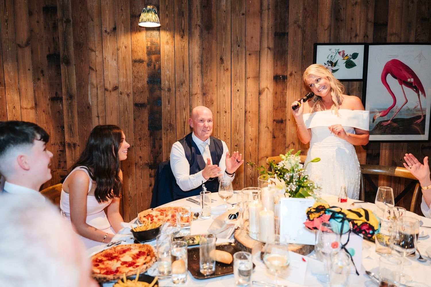 Wedding guests gather around a rustic wooden table for dinner while sharing laughter and conversation. The Dean Dublin Wedding Photographer