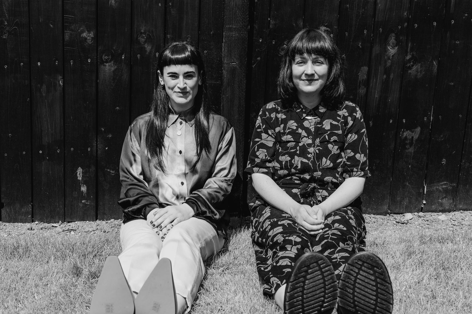 Vintage black and white photograph of two women in 1920s attire sitting side by side on a bench outdoors. PHOTOGRAPHER Dublin ireland