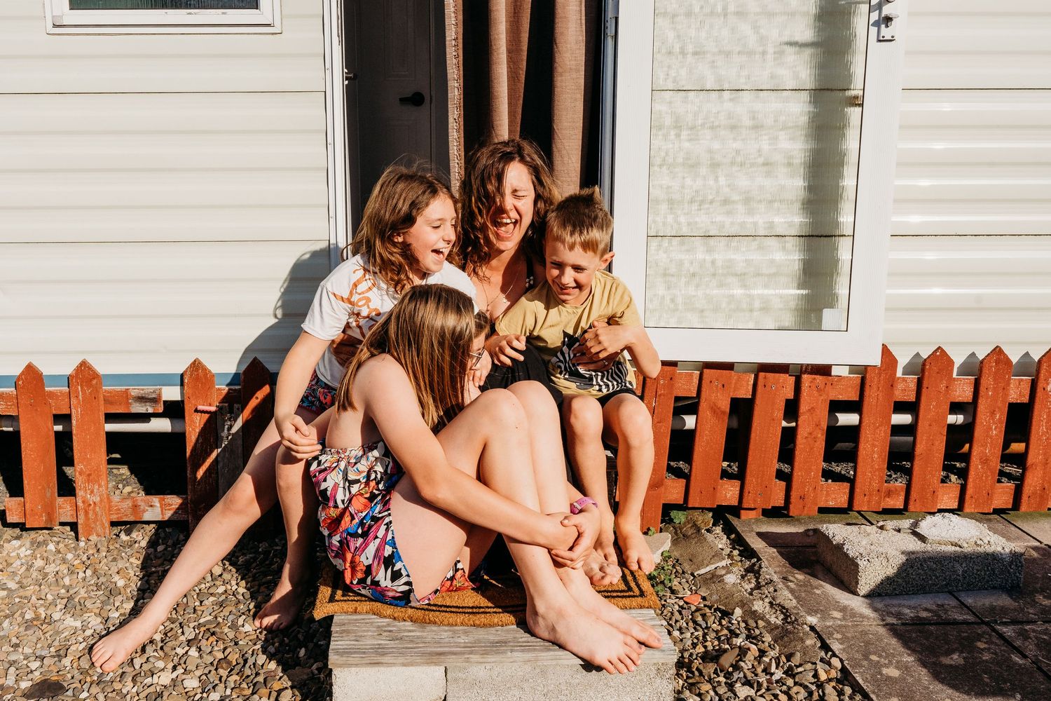 A joyful group shares laughter together while sitting on outdoor steps during golden hour. family PHOTOGRAPHER Dublin