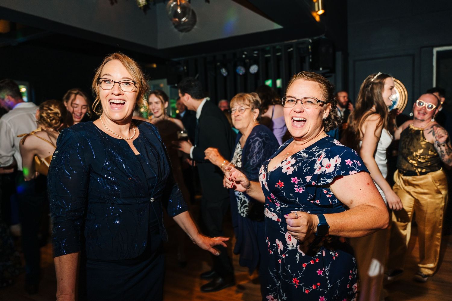 Poulaphouca Wedding photographer wicklow  Party guests laughing and dancing together on a crowded indoor dance floor at a celebration.