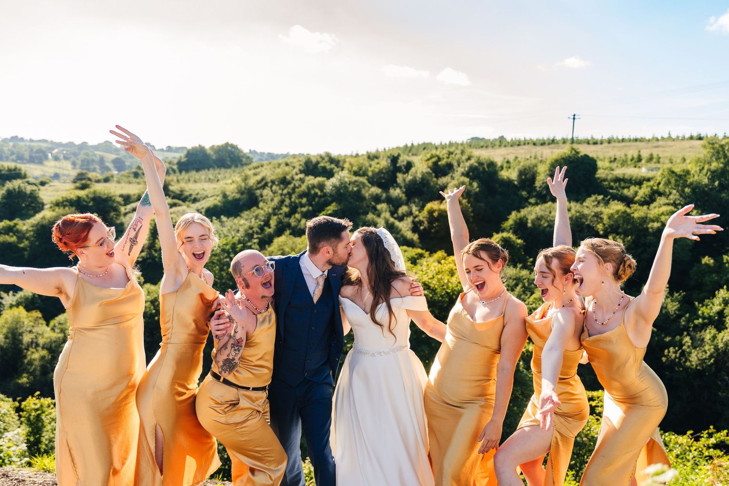 Poulaphouca Wedding photographer wicklow  Wedding party in yellow dresses poses joyfully against scenic countryside backdrop.