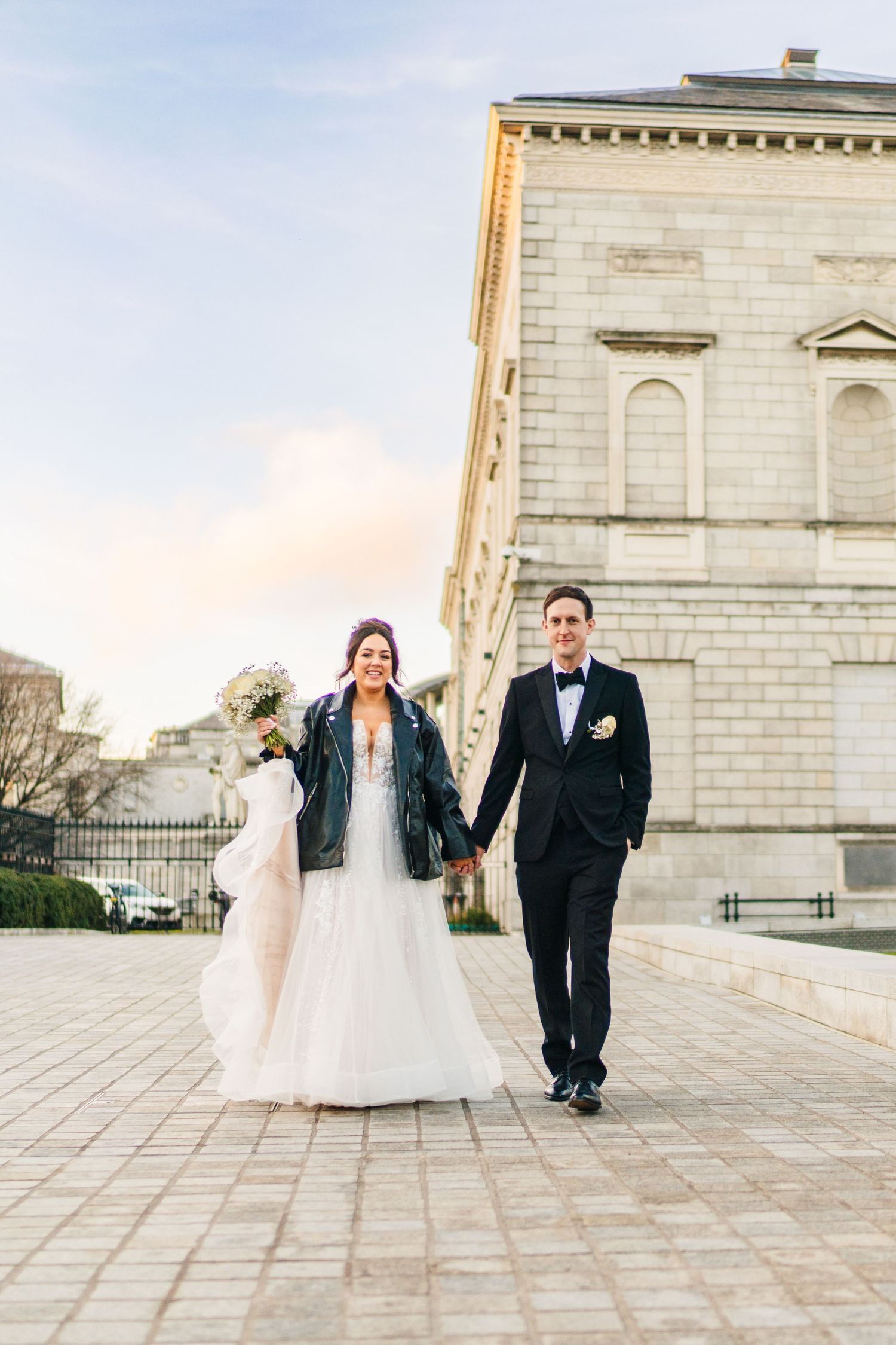 Couple taking wedding photos outside a grand stone building during golden hour. Wedding PHOTOGRAPHER Dublin