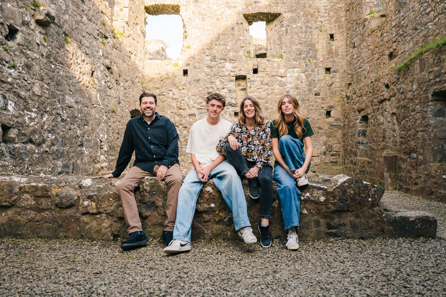 A group of people sitting casually together on stone ruins during a sunny day. Photographer Ireland dublin