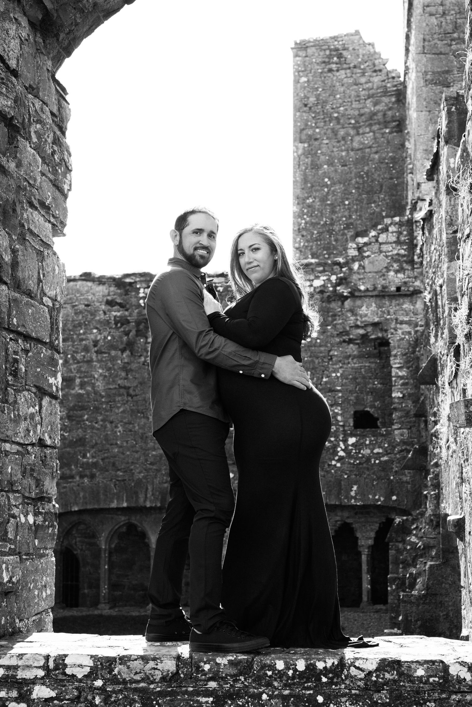 Black and white photo series showing couple posing playfully in historic ruins. Family PHOTOGRAPHER Dublin