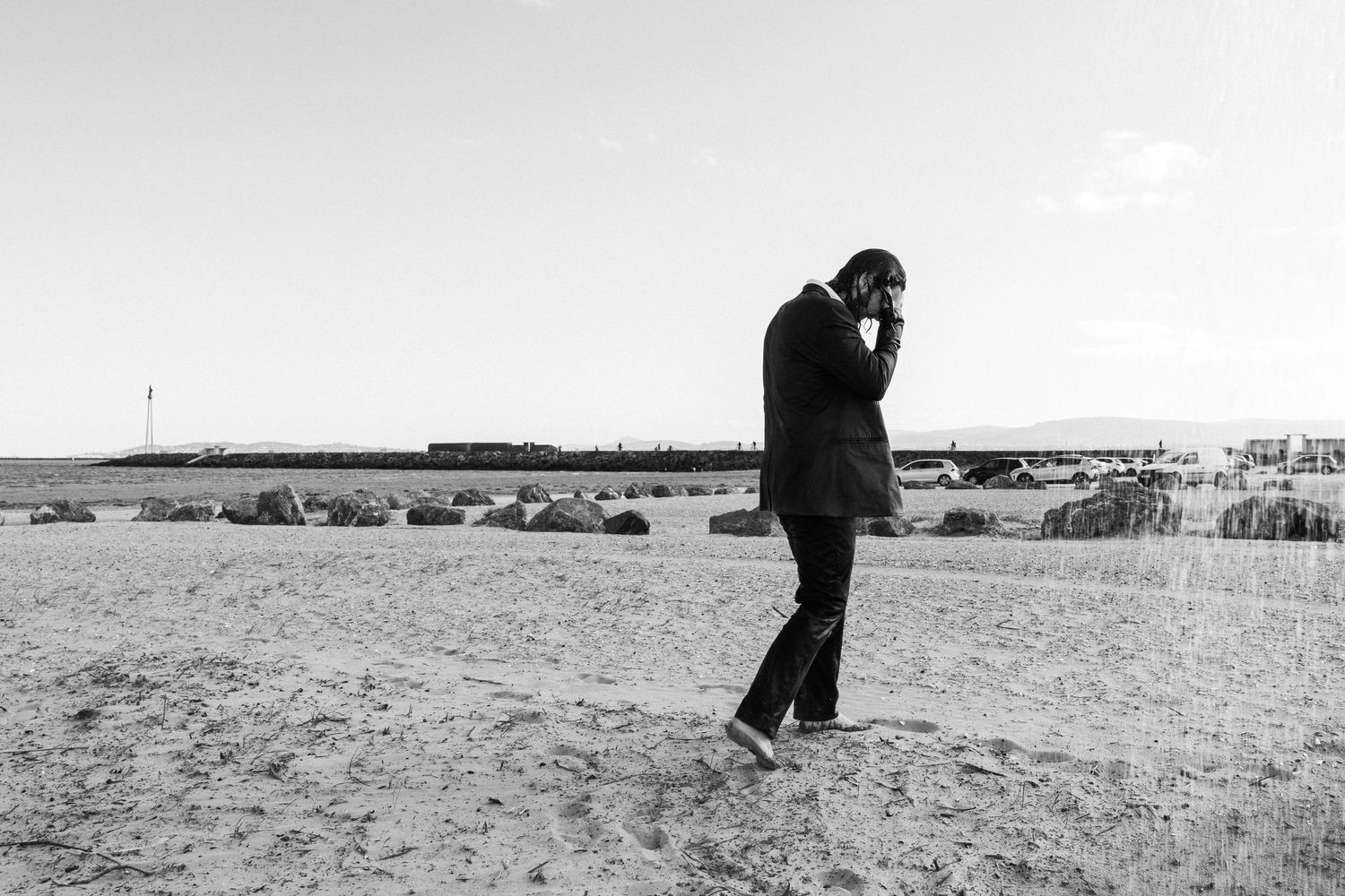 A figure in dark clothing stands on a windswept beach on an overcast day. PHOTOGRAPHER Dublin