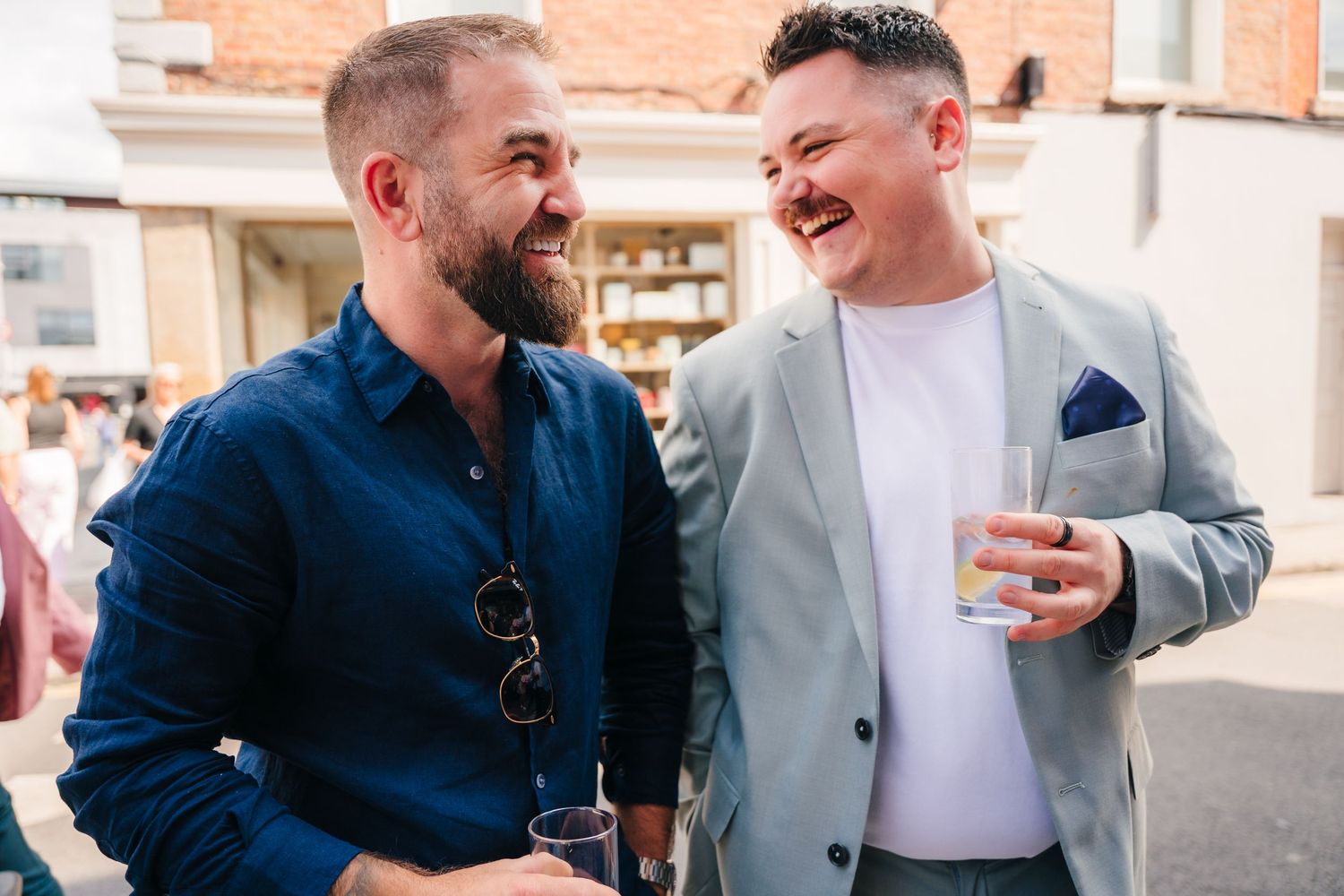 Friends sharing drinks and laughter at casual outdoor gathering. Same sex wedding PHOTOGRAPHER Dublin