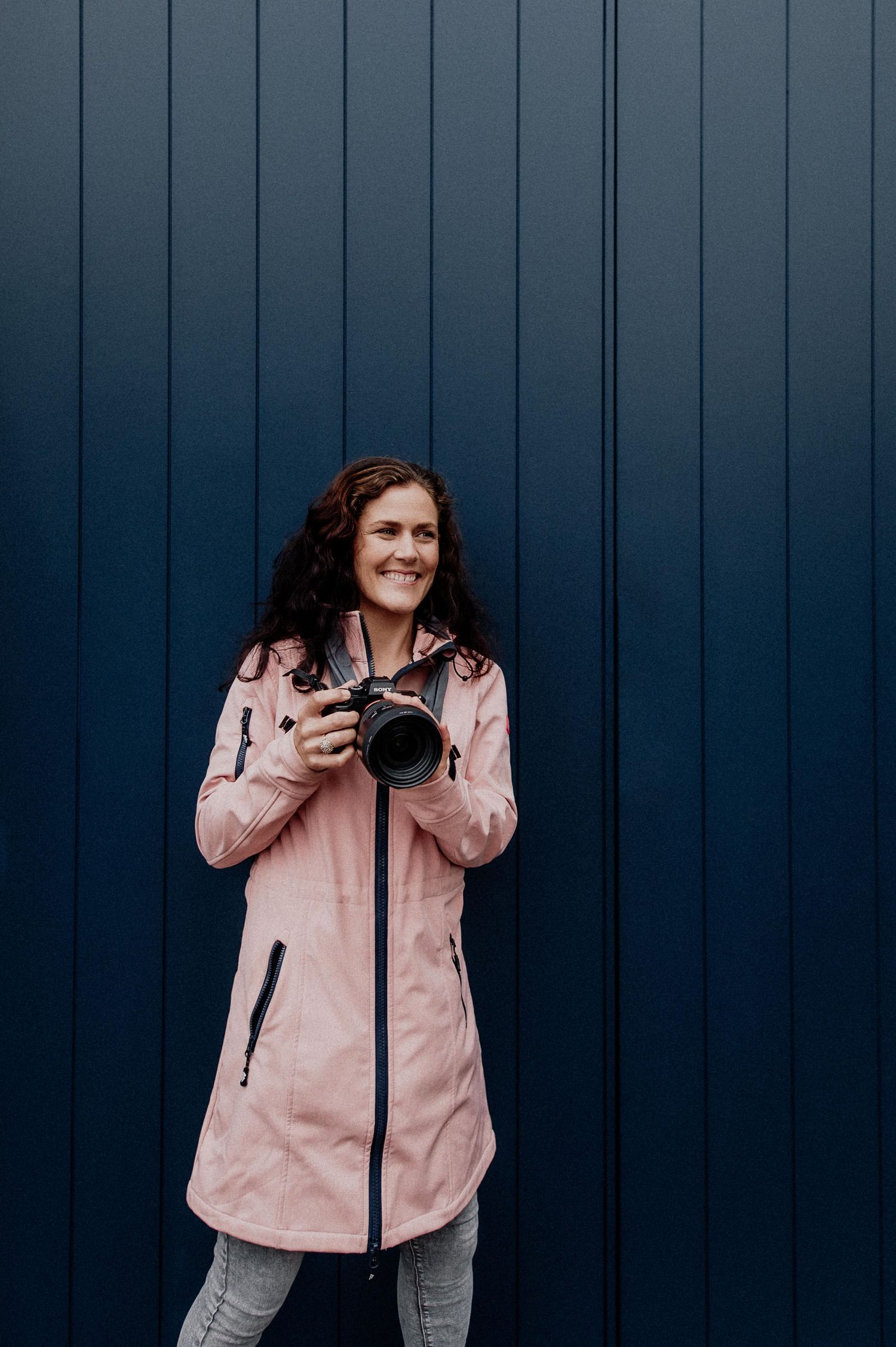 A person in a pink windbreaker jacket poses against a dark blue wall in a four-panel photo sequence. wedding photographer dublin
