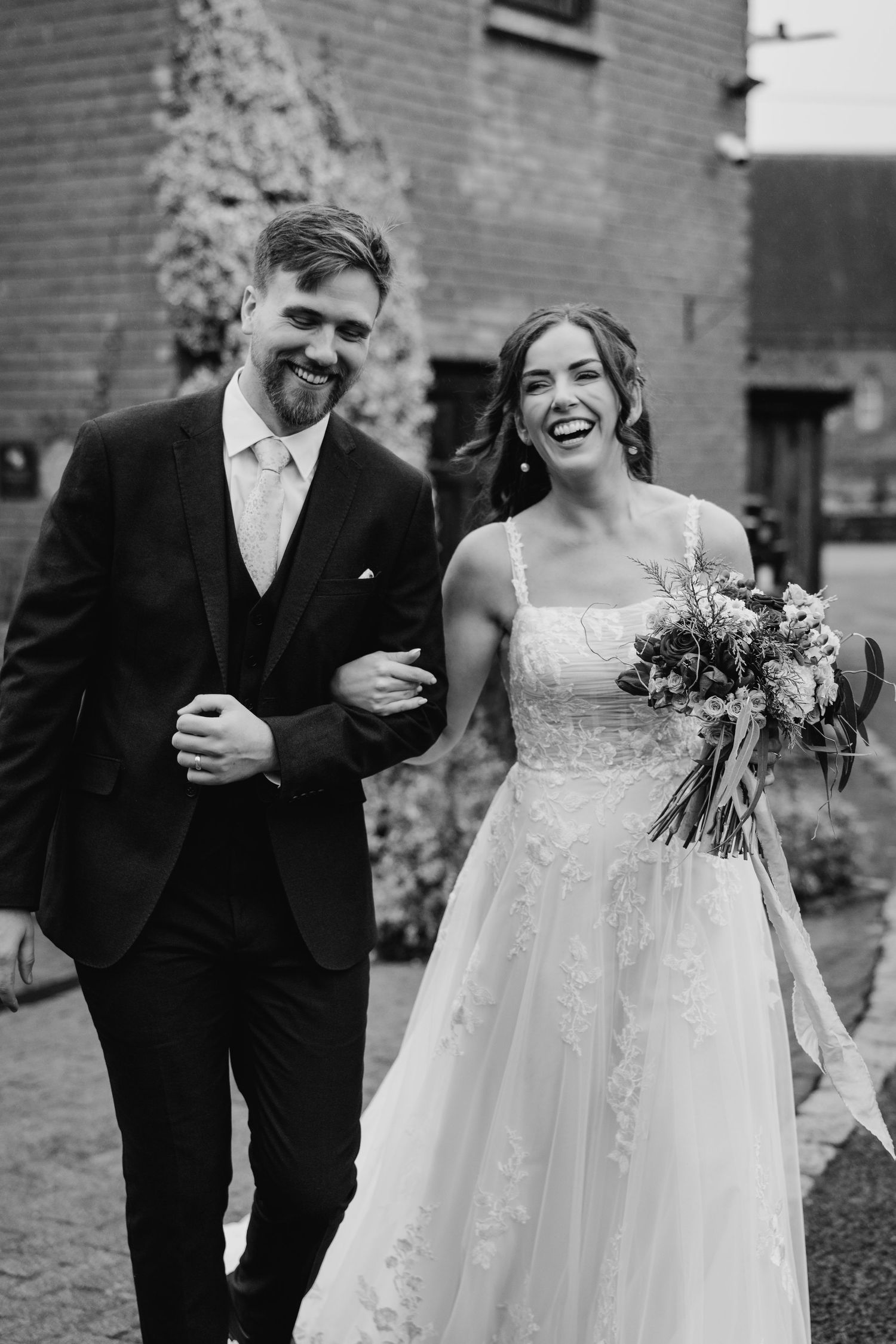 A joyful black and white wedding photo of a couple laughing together, with the bride holding a floral bouquet. Wedding photographer Dublin