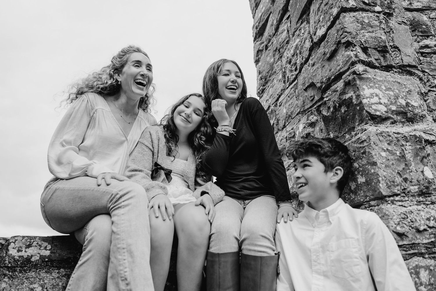 Group laughing together while sitting outdoors in black and white photography. BEctive abbey family photographer dublin