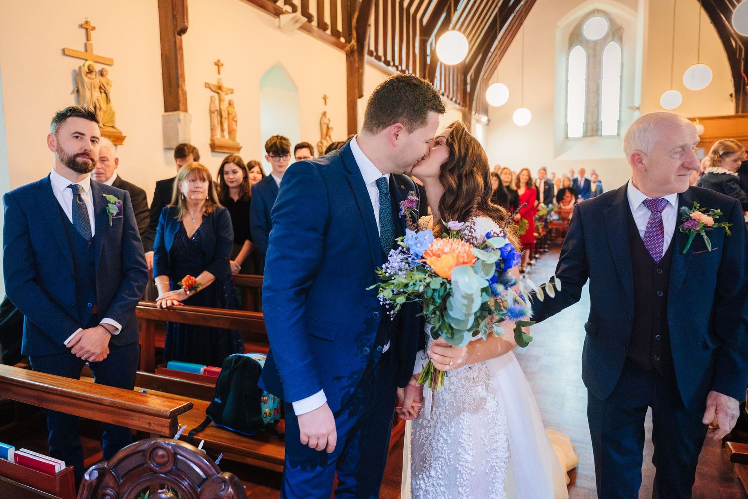 Wedding ceremony in a beautiful church with wooden beams and stained glass windows.