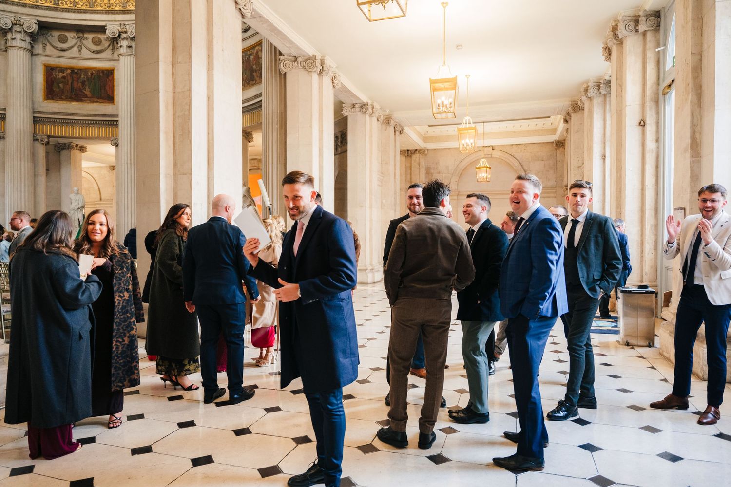Grand hallway with columns and checkered floor filled with formal event guests. Wedding photographer dublin