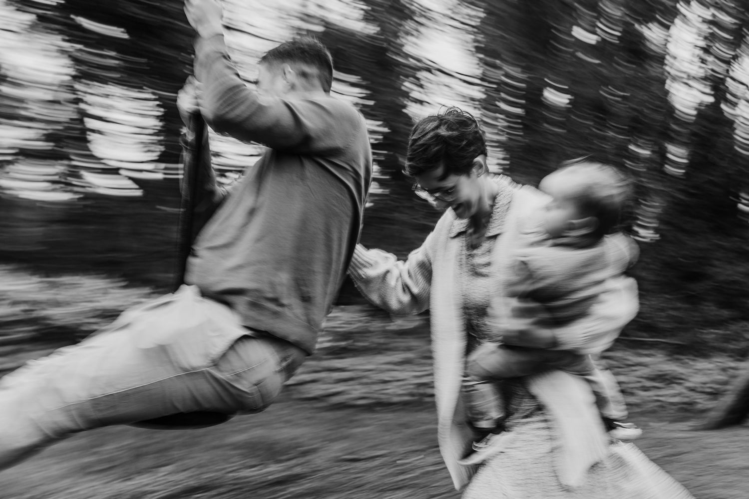 Family photographer Dublin IrelandMotion-blurred black and white photograph showing people running through a wooded area in a playful scene.