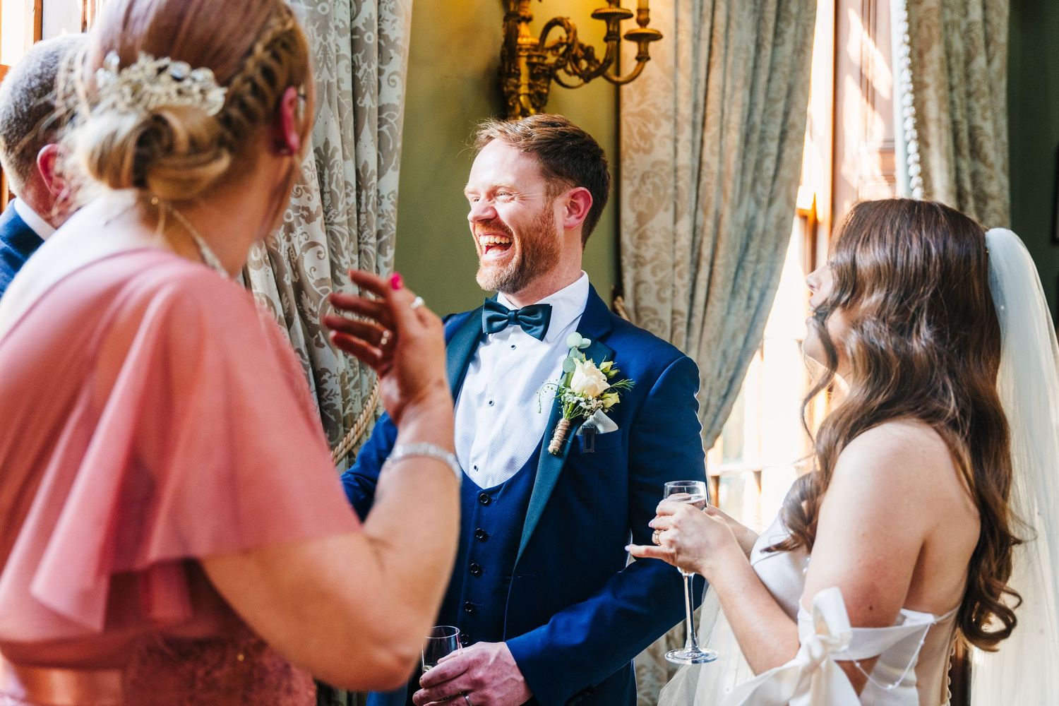 Castle Leslie Wedding Photographer DuCandid moment of joyful laughter during a wedding reception while guests converse in an elegant venue.