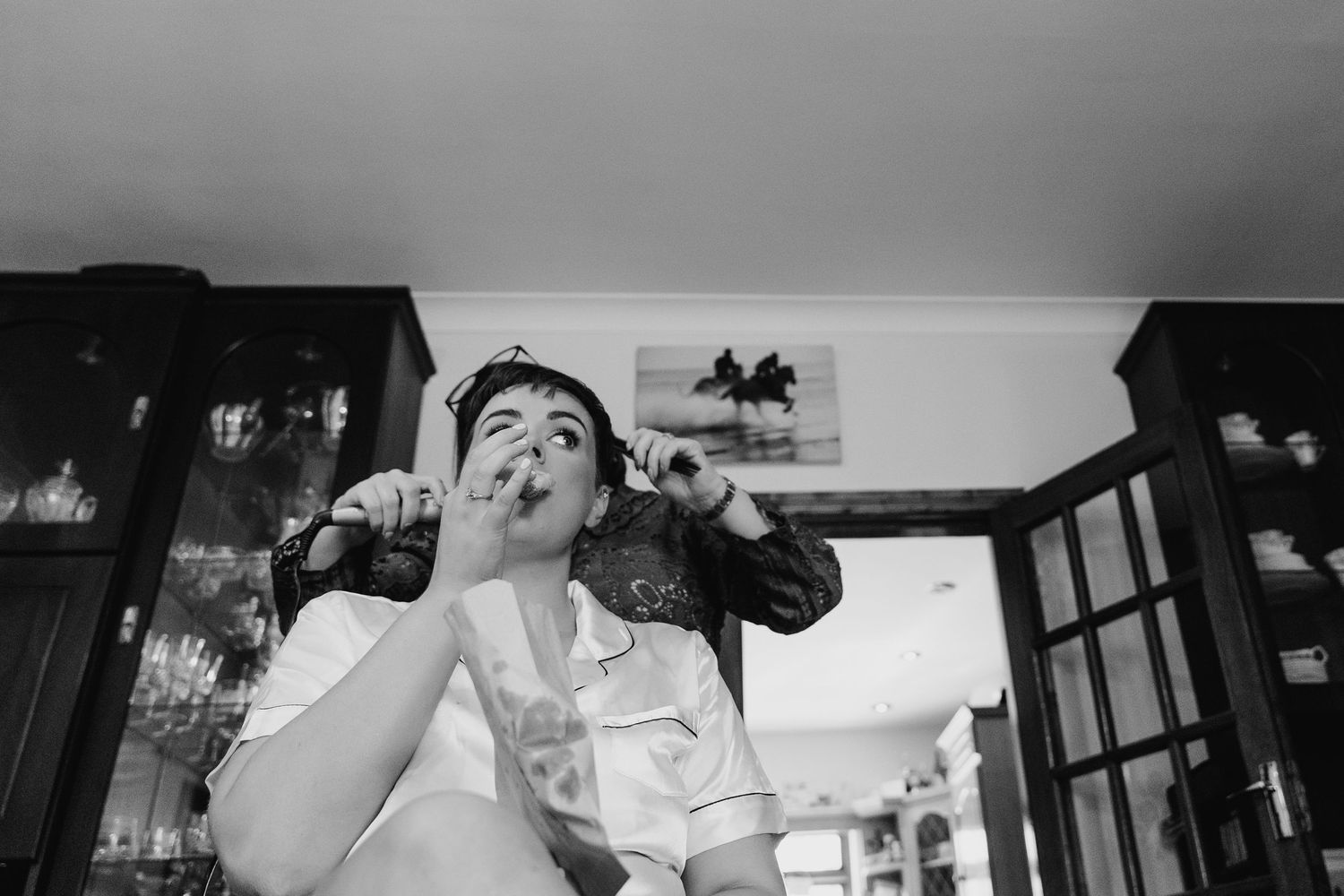 A black and white photo of someone joyfully singing or shouting while holding a drink at a bar or restaurant. Millhouse slane wedding photog