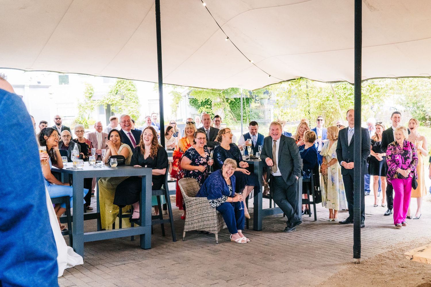Poulaphouca Wedding photographer wicklow  Wedding guests seated under a white tent watch the ceremony proceedings.