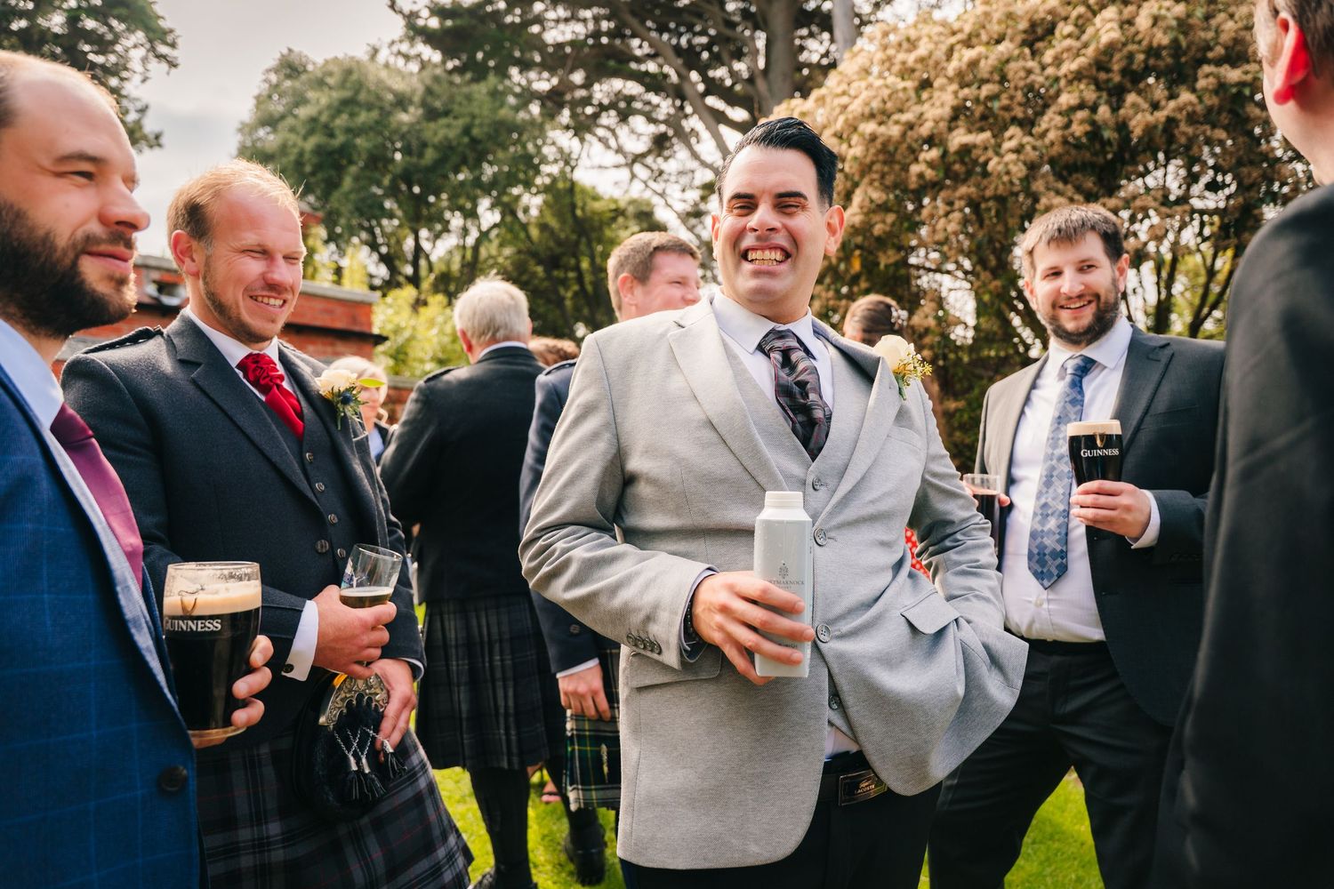 Wedding guests toasting and celebrating outdoors with drinks in hand. Portmarnock Hotel Wedding PHOTOGRAPHER Dublin