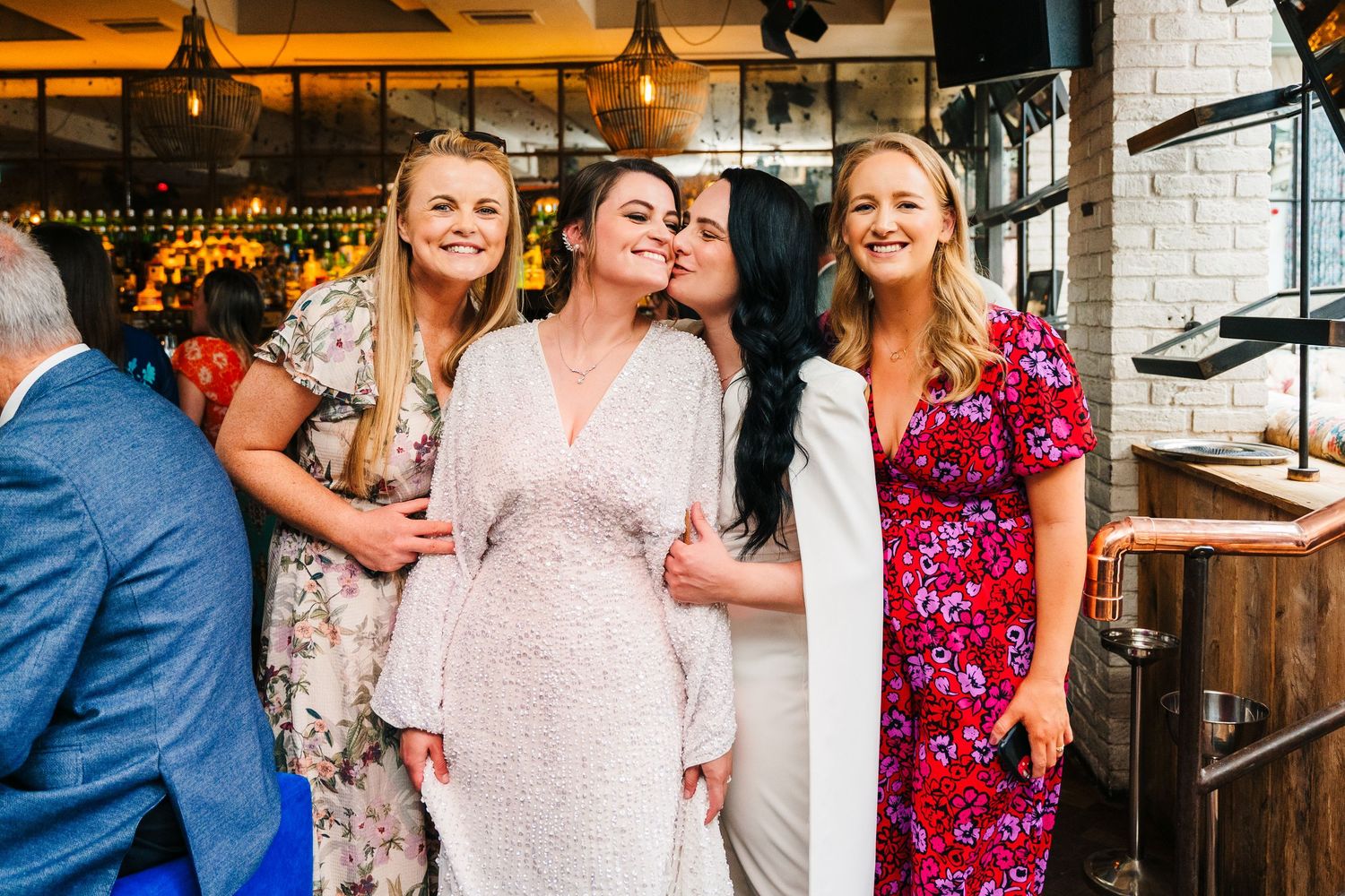 A celebratory moment shared between friends at a rustic bar venue with brick walls. House Dublin Wedding Photographer