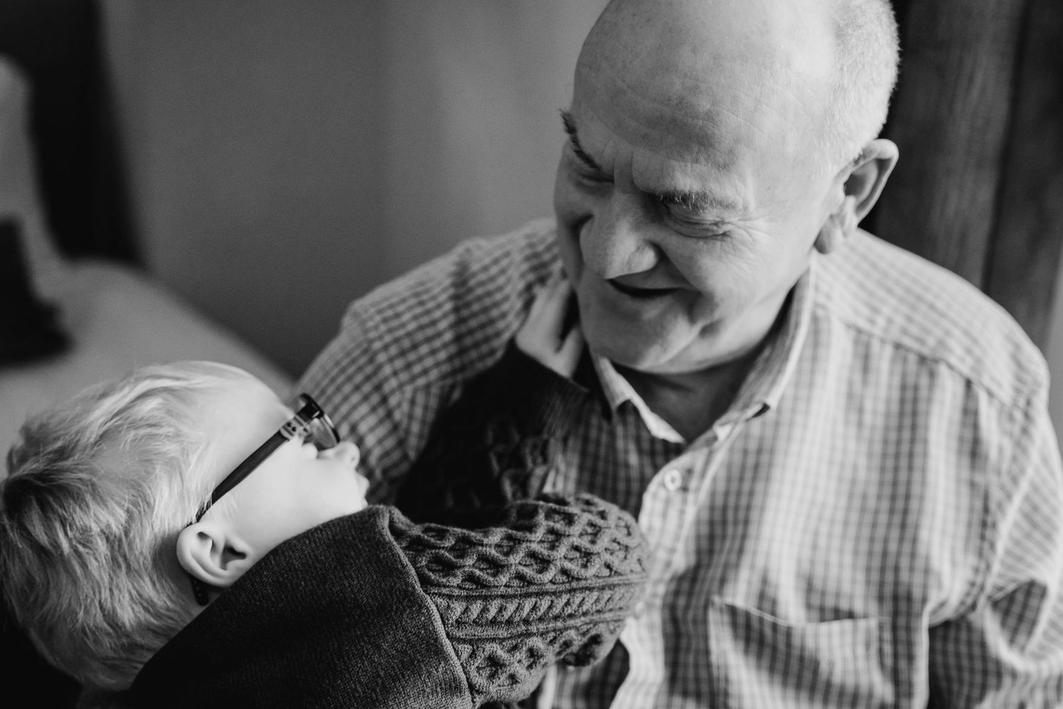 Black and white photo showing loving moment between parent and laughing child in a casual indoor setting.  Wedding PHOTOGRAPHER Trim Castle