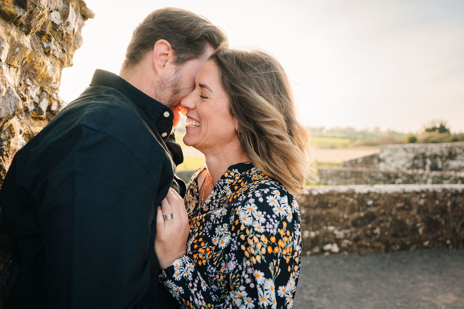 A couple in formal attire embrace and kiss on stone steps during sunset. Photographer Ireland dublin
