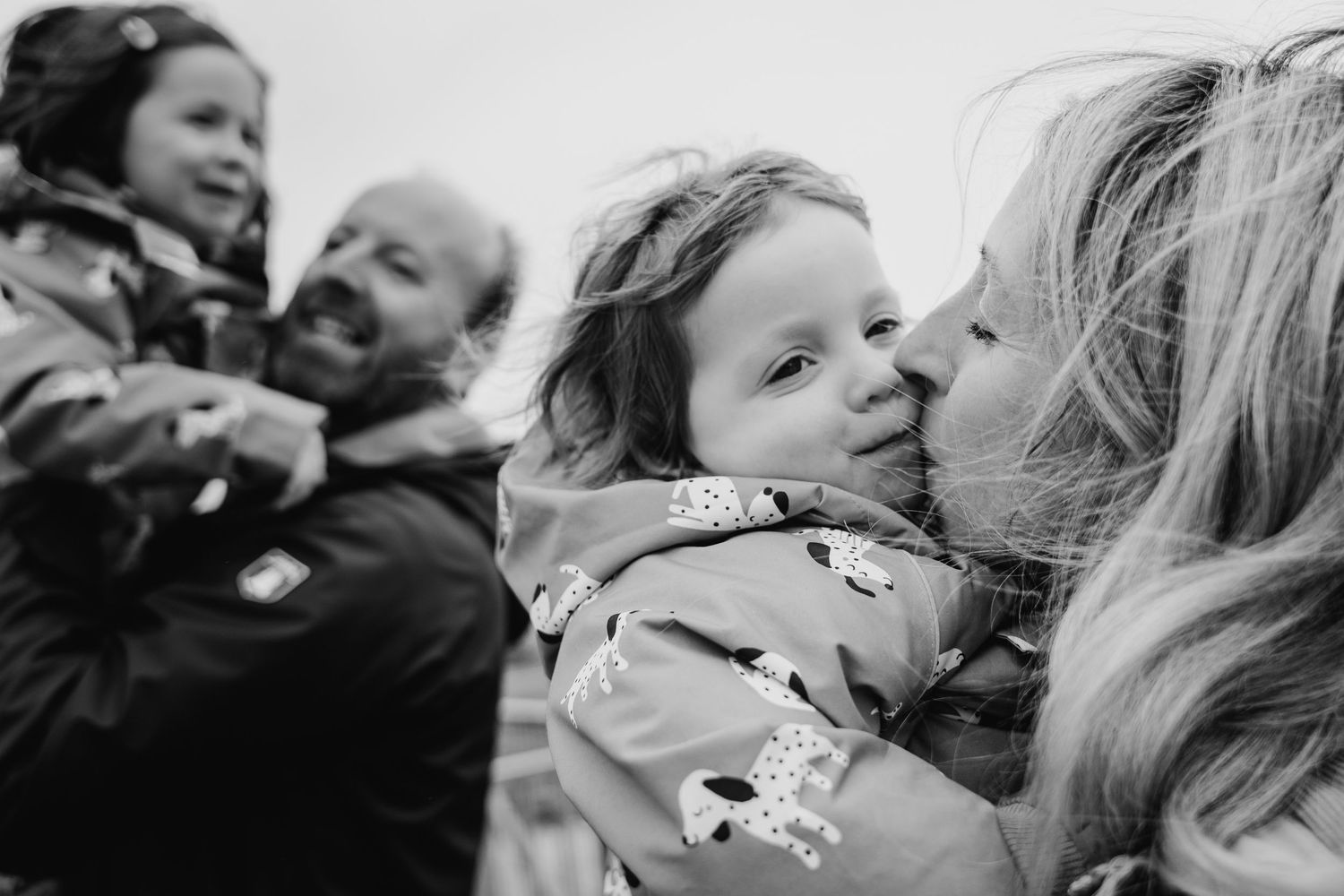 Black and white candid photograph showing tender family moments of love and affection outdoors. PHOTOGRAPHER Dublin