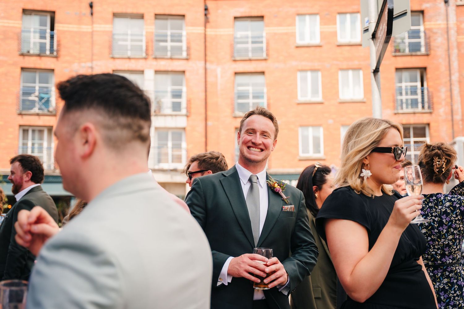 Group of well-dressed people mingling at an outdoor social gathering. Same sex wedding PHOTOGRAPHER Dublin