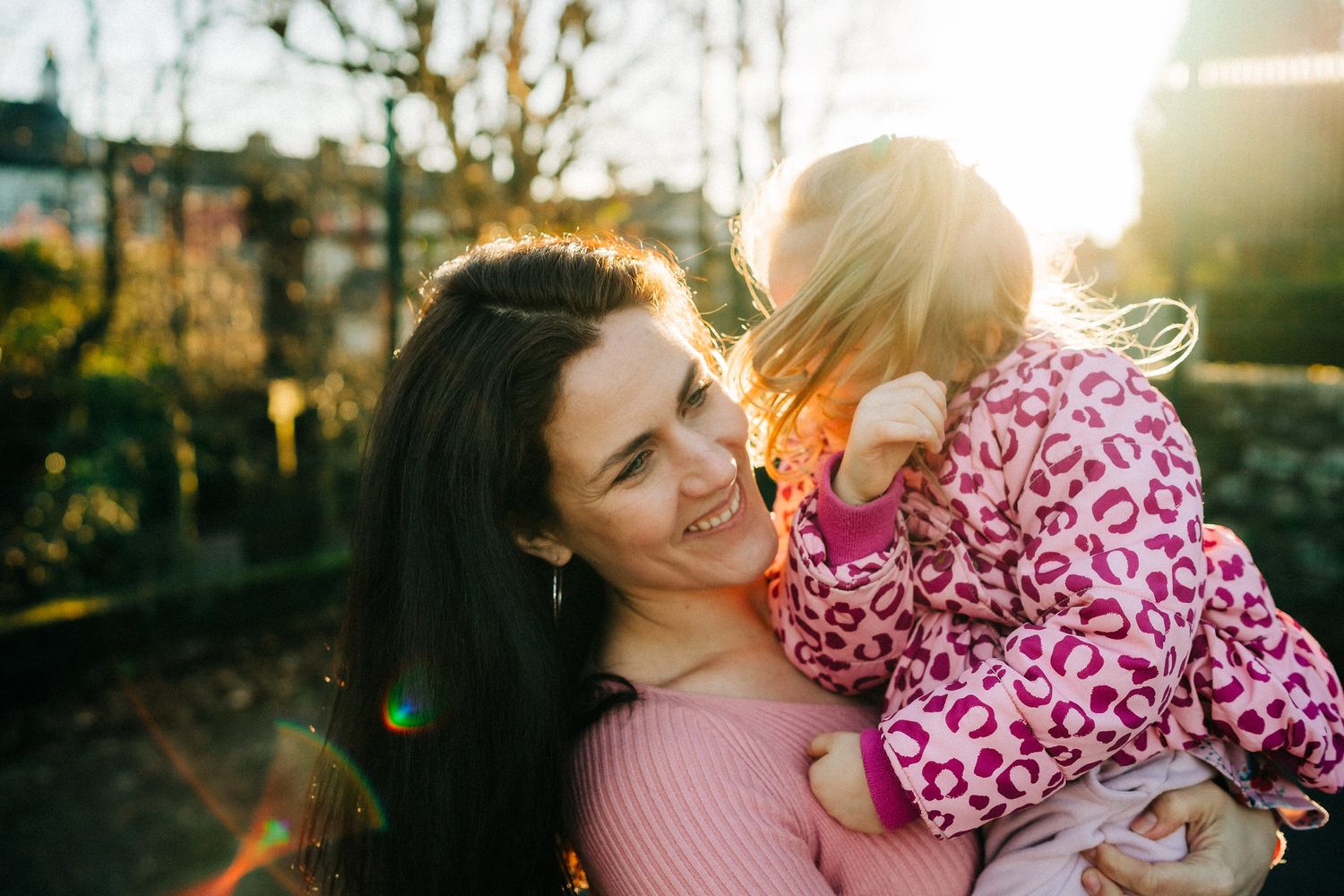 A joyful parent-child moment captured in sunlit winter park with warm glowing bokeh effect and matching outfits Ireland Family photographer