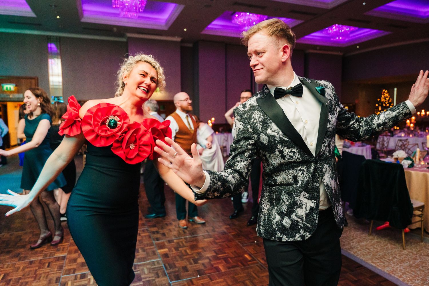 Dancers in formal attire perform together at an elegant ballroom event with purple mood lighting overhead. Wedding PHOTOGRAPHER Dublin