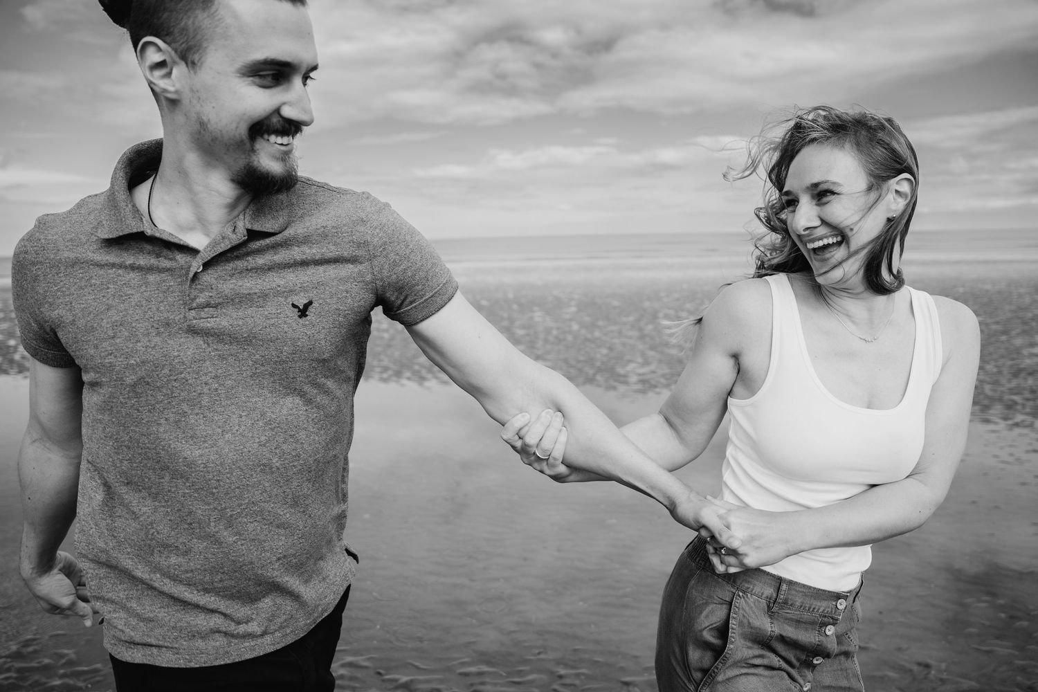 A black and white panoramic collage of a happy couple dancing and laughing together at the beach. PHOTOGRAPHER Dublin ireland