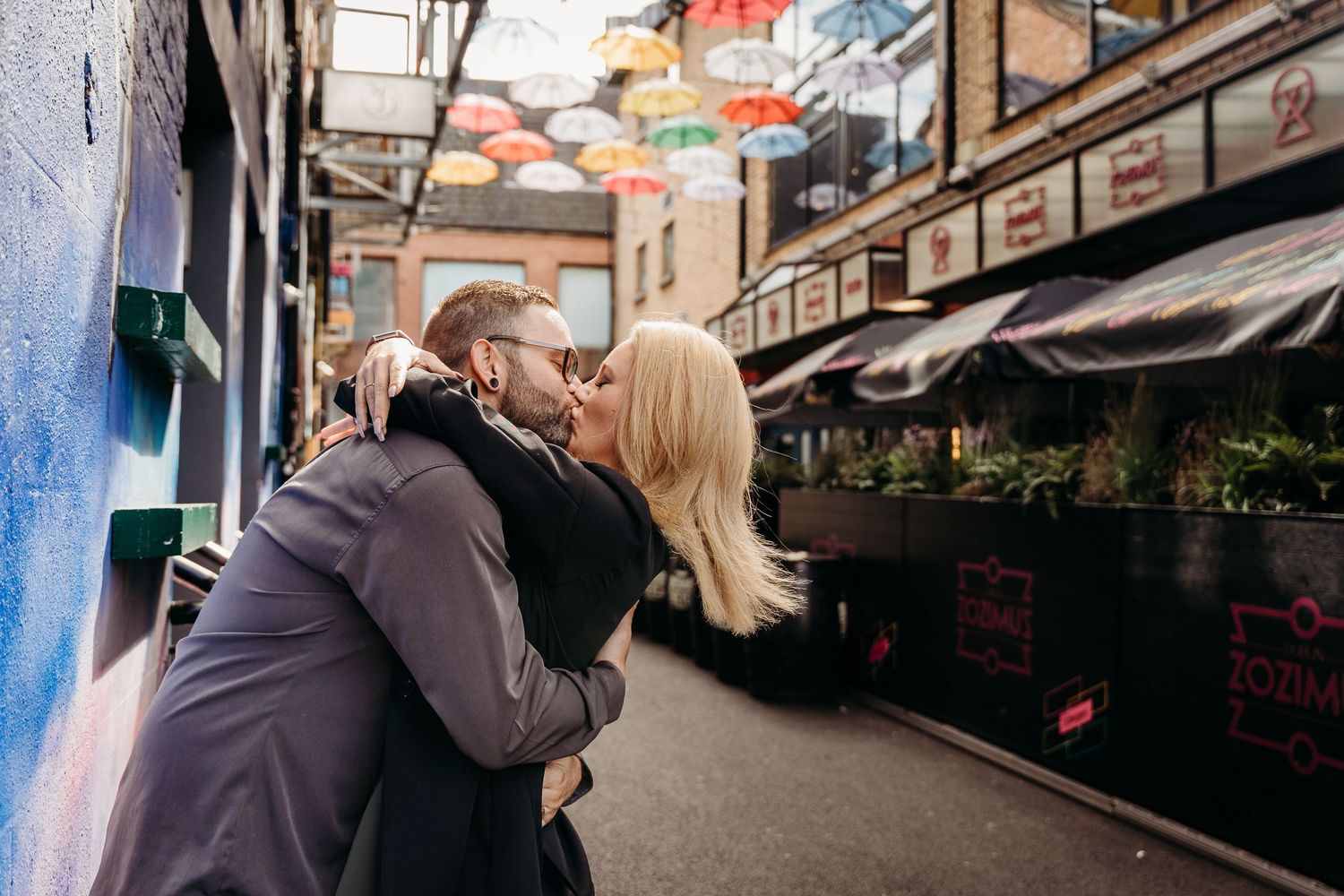Group of people walking through a covered outdoor shopping arcade with storefronts and hanging decorations. PHOTOGRAPHER Dublin ireland