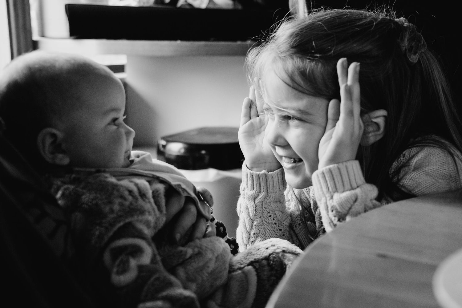 Black and white candid photo showing two young children playing together at home. family PHOTOGRAPHER Dublin