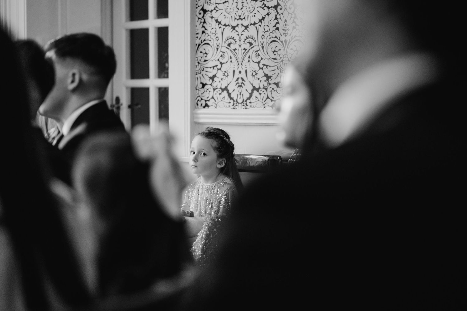 Black and white artistic shot of wedding guests gathered in an elegant interior space.  Virginia Park Lodge Wedding Photographer Cavan Dubli