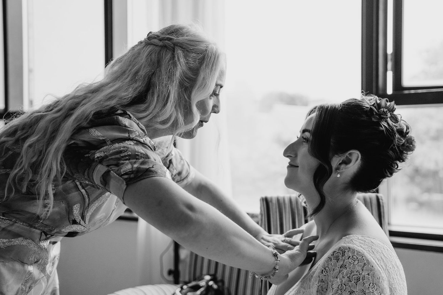 A tender black and white moment between two people during wedding preparations by a window. Wedding Photography Trim Castle Ireland