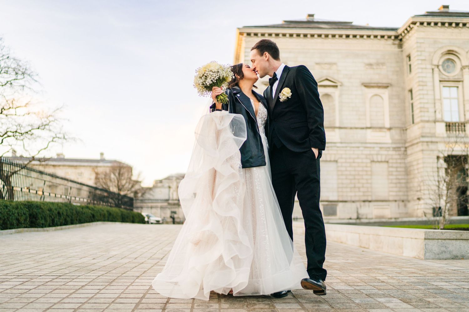 A couple shares a romantic moment outside a grand stone building on their wedding day. Wedding PHOTOGRAPHER Dublin