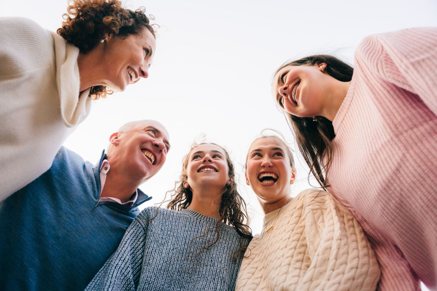 Family photographer Ireland Dublin Low angle view of five people in a circle laughing and enjoying a lighthearted moment together.