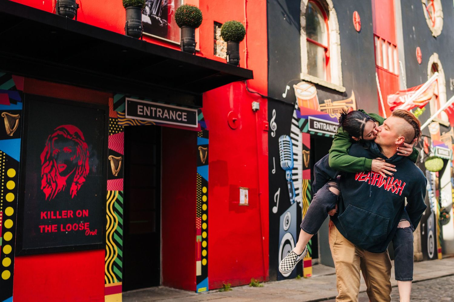 Row of red storefronts with neon signs and entrance markings along an urban street. PHOTOGRAPHER Dublin Ireland