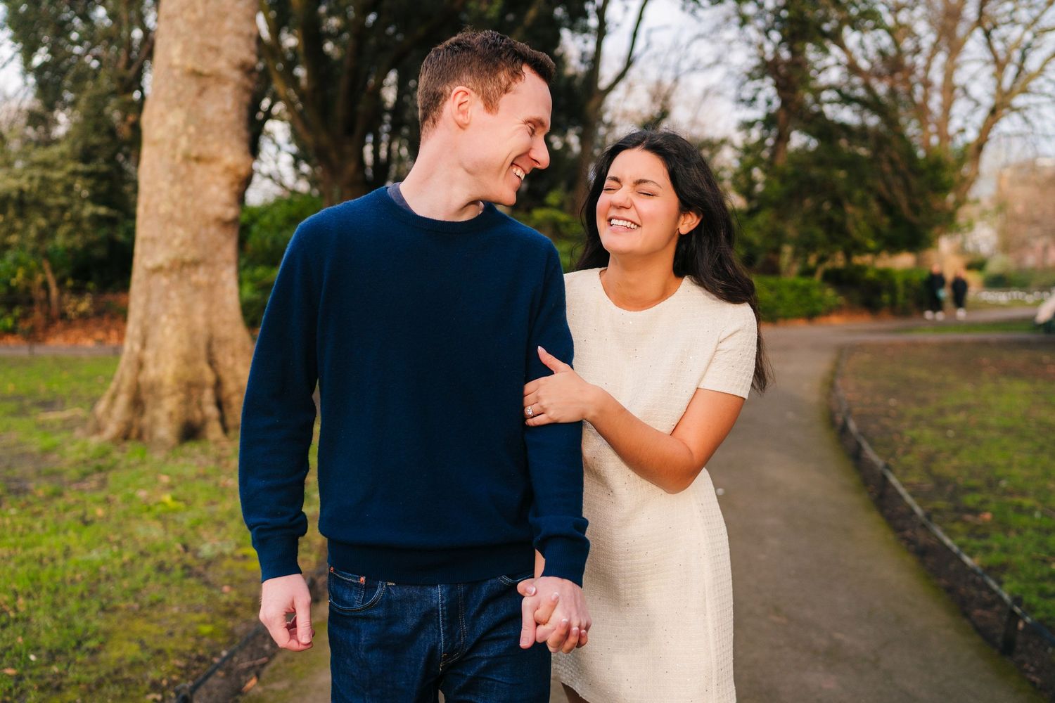 A couple walking and laughing together on a pathway in a park during autumn. Surprise proposal dublin photography